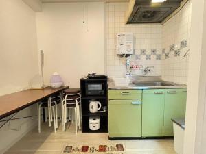 una cocina con armarios verdes y una encimera con fregadero en マルチステイ大阪難波53, en Osaka