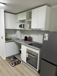 a kitchen with white cabinets and a black refrigerator at departamento papudo punta puyai piso 1 in Papudo