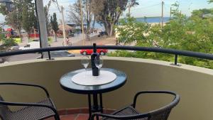 a table with two wine glasses on a balcony at Amaneceres frente al Mar Dpto 2 in Puerto Madryn