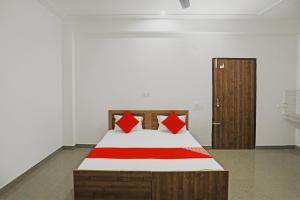 a bedroom with a bed with red pillows on it at OYO Flagship Hotel Yuvraj Plaza in Garhi Harsāru