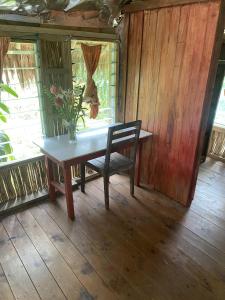 a table with a chair and a vase of flowers on it at Port-Olry Beach Bungalows Chez Louis in Port Olry