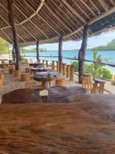 a restaurant with tables and chairs on the beach at Port-Olry Beach Bungalows Chez Louis in Port Olry