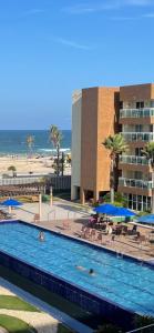 una piscina junto a una playa y un edificio en Apart Vg Fun, en Fortaleza