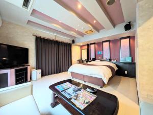 SKY Ocean-terace Omura في Omura: غرفة نوم بسرير وتلفزيون وطاولة