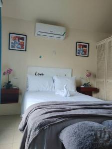 Un dormitorio con una cama blanca con un signo de amor. en Orchid Inn en Montego Bay