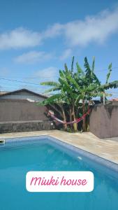 una piscina con una palmera al lado de una casa en Casa de Praia com Piscina em Peruíbe, en Peruíbe