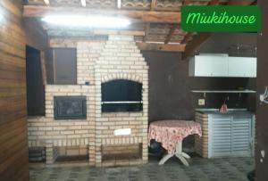 una chimenea de ladrillo con una mesa delante en Casa de Praia com Piscina em Peruíbe, en Peruíbe