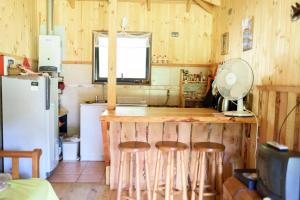 a kitchen with a counter with stools and a refrigerator at Cabaña en Caburgua in Caburgua