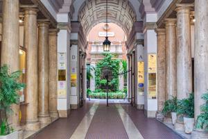 un couloir dans un bâtiment avec colonnes et plantes dans l'établissement Karisma Suites, à Rome