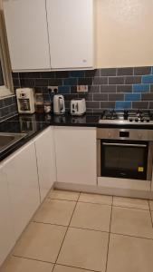 a kitchen with white cabinets and a stove at 3BED Maisonette Near CityCentre in Birmingham