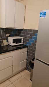 W kuchni znajduje się biała lodówka i kuchenka mikrofalowa. w obiekcie 3BED Maisonette Near CityCentre w Birmingham