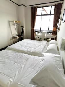 1 dormitorio con 2 camas blancas y ventana en A scenic Malacca retreat (New reno unit Nov 23), en Melaka