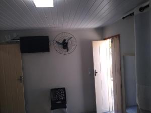 a clock on the wall of a room with a fan at Suites Amarylis in Mucugê
