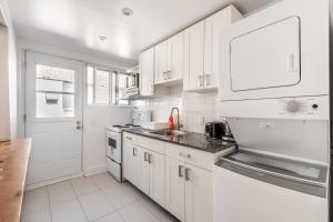 una cocina blanca con armarios blancos y fregadero en Cozy one bedroom apartment in the heart of downtown - 329, en Montreal