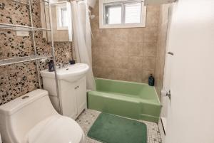 y baño con aseo y bañera verde. en Cozy one bedroom apartment in the heart of downtown - 329, en Montreal