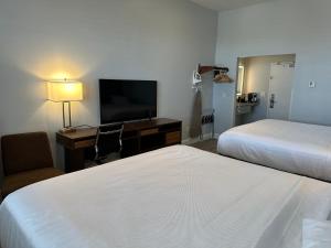 Habitación de hotel con 2 camas, escritorio y TV. en Hotel Skye San Francisco Airport SFO FREE SHUTTLE!, en San Bruno