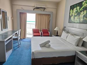 a hotel room with a bed and two red chairs at beachfront sea in Tanjung Bungah