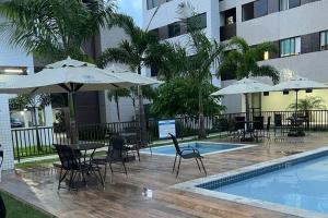 a pool with tables and chairs and umbrellas next to a building at Apartamento Moderno e Tranquilo in Recife