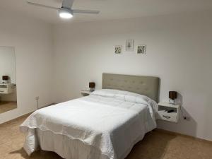 a white bedroom with a bed and a ceiling fan at Bella Luna apart in Mina Clavero