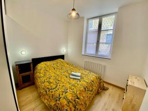 a bedroom with a bed with a yellow blanket and a window at Cathedral: Cosy in the heart of the city center in Poitiers