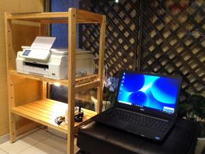 un computer portatile seduto su una scrivania accanto a una stampante di WEB Hotel Tokyo Asakusabashi / Vacation STAY 8771 a Tokyo