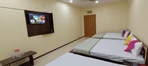 a bedroom with two beds and a window with a tv at aapka ujjain homestay in Ujjain