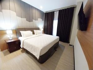 a hotel room with a bed and a night stand at Grand Verona Samarinda in Samarinda