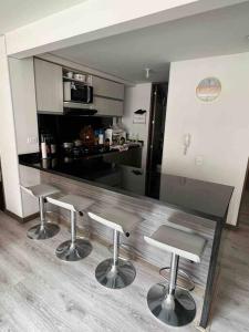 una cocina con 3 taburetes y una barra en apartamento privado en Bogotá