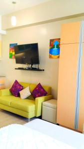 ein Wohnzimmer mit einem gelben Sofa und einem Flachbild-TV in der Unterkunft Studio-Type Condo at Eastwood Legrand 3 in Manila