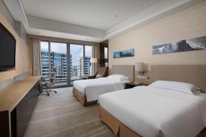 a hotel room with two beds and a flat screen tv at Crowne Plaza Guangzhou Huadu, an IHG Hotel in Guangzhou