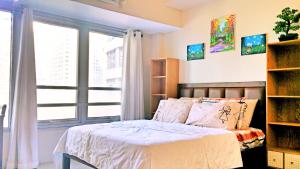 ein Schlafzimmer mit einem Bett und einem großen Fenster in der Unterkunft Studio-Type Condo at Eastwood Legrand 3 in Manila