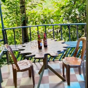 Munnar green portico cottage في مونار: طاولة خشبية مع زجاجتين وكرسيين