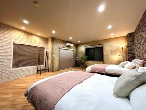 a bedroom with two beds and a brick wall at S-asakusa in Tokyo