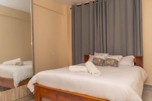 1 dormitorio con 2 camas y espejo en Arabella Apartments en Bungoma