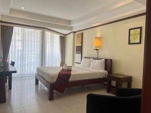 um quarto com uma cama, uma secretária e uma janela em Khon Kaen Orchid Hotel em Khon Kaen