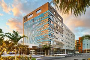 AC Hotel by Marriott Miami Airport West/Doral في ميامي: وجود عمارة طويلة فيها نخيل