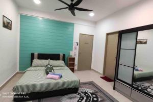 a bedroom with a bed and a green wall at Nurul Homestay Ajil in Bukit Payong