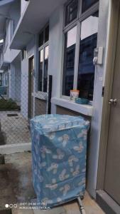 a blue suitcase sitting outside of a building at Nurul Homestay Ajil in Bukit Payong