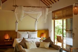 a bedroom with a bed and a couch in a room at Alba Wellness Resort By Fusion in Hue +151 photos
