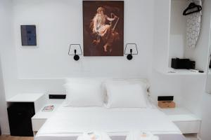 Athens Muses Suites في أثينا: غرفة نوم بسرير ابيض ولوحة على الحائط