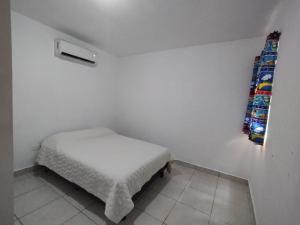 una piccola camera bianca con un piccolo letto di Departamento Azul Marino Cerritos a Mazatlán