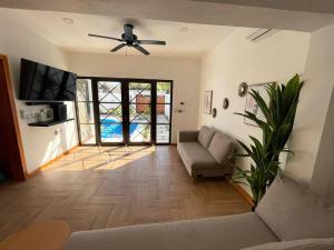 een woonkamer met een bank en een plafondventilator bij Casa AbrahamMya Playa Linda 3 bed home with pool. in El Desengaño
