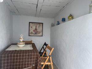 een tafel en een stoel in een kamer met een tafel en een foto bij Casa Miguelito in Comares