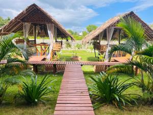 a wooden walkway leading to a resort with two huts at La Palapa Inn Port Barton in San Vicente