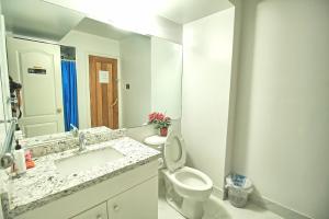 a white bathroom with a toilet and a sink at Soho, Comfortable with Free Parking Spot on basement in Vaughan