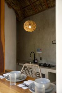 a dining room table with plates and a light fixture at Casa MexiBali, Palapa 47 in Troncones