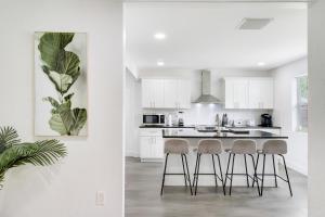 a kitchen with white cabinets and a kitchen island with stools at Rockaway Beach House in West Palm Beach