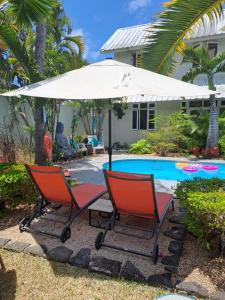 two chairs under an umbrella next to a pool at Explora Prestige in Blue Bay