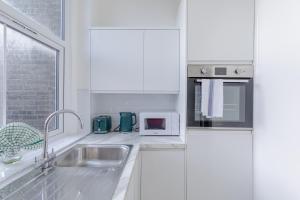 a white kitchen with a sink and a microwave at HAFH in Paddington - Double studio 1 in London