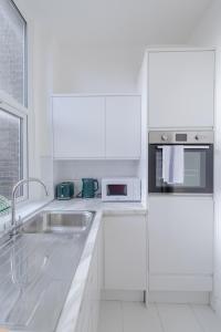 a white kitchen with a sink and a microwave at HAFH in Paddington - Double studio 1 in London